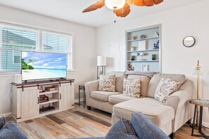 Ein Wohnzimmer mit Fernseher, einer Couch, einem Couchtisch und einem Bücherregal.
