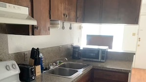 Una cocina con armarios de madera, una estufa blanca, un fregadero y un microondas.