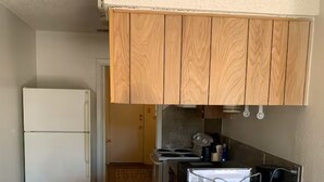 Una cocina con armarios de madera, un refrigerador, una estufa y dos taburetes de bar.