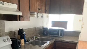 Una cocina con armarios de madera, una estufa blanca, un fregadero y un microondas.