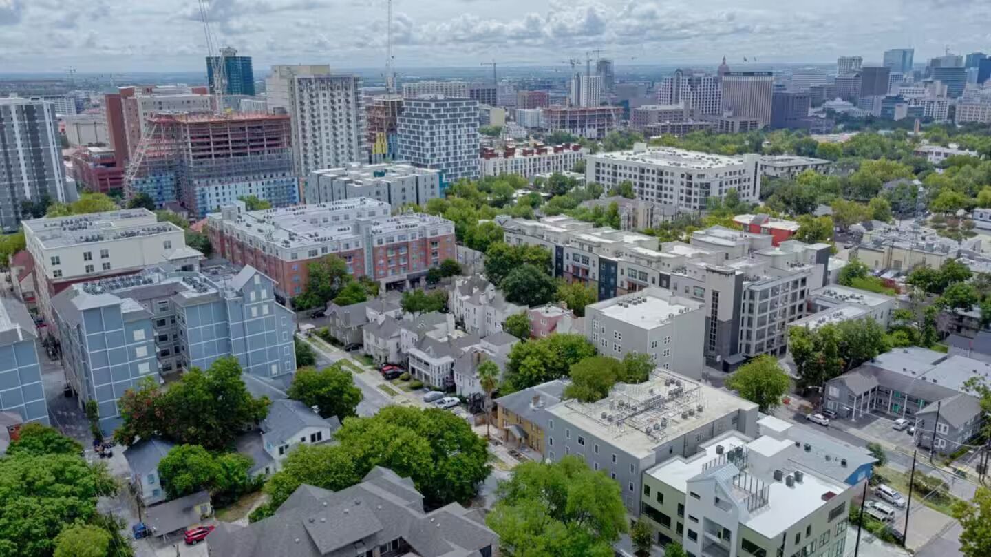 Un paisaje urbano con diversos edificios, incluyendo viviendas y estructuras comerciales, además de varias obras en construcción.