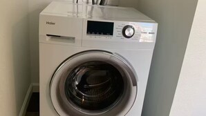 Eine Haier Waschmaschine mit Frontlader in einem Waschraum mit Holzboden und weißen Wänden.