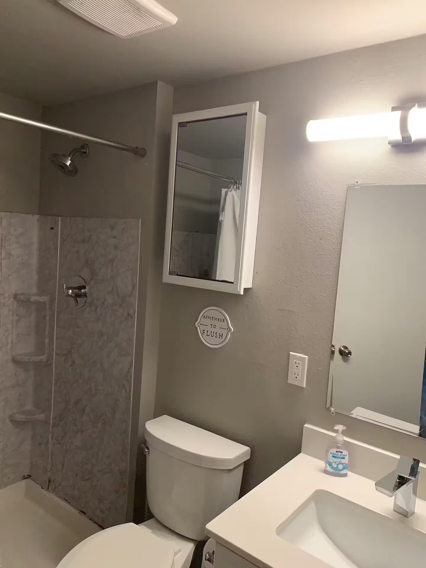 Une salle de bain équipée d’une douche, de toilettes, d’un lavabo et d’un miroir.