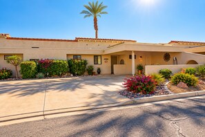 A hotel with a paved driveway, palm trees, and landscaped flower beds. - 14th Fairway Retreat | Solar, Battery & EV Charger (Palm Desert)