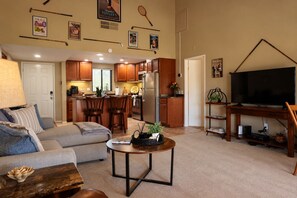 A living room with a sofa, a coffee table, and a TV stand with a flat-screen TV. - 14th Fairway Retreat | Solar, Battery & EV Charger (Palm Desert)