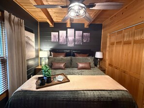 A bedroom with a bed, headboard, pillows, bedside tables, lamps, a ceiling fan, artwork on the wall, and a window with blinds. - Silver Maple Summit | Hot Tub, Game Loft, Prime Gatlinburg Location-Pet firendly-Free Tickets (Gatlinburg)