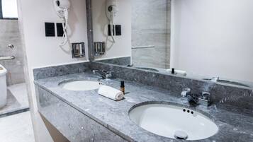Baño con dos lavamanos, un secador de pelo y una toalla.