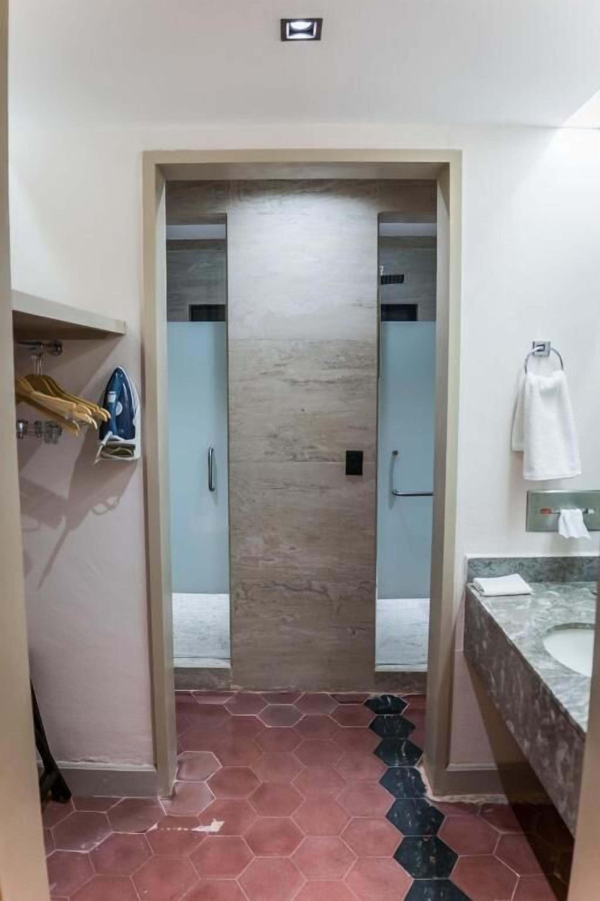 A bathroom with a hexagonal tile floor, a towel rack, and a sink with a marble countertop.