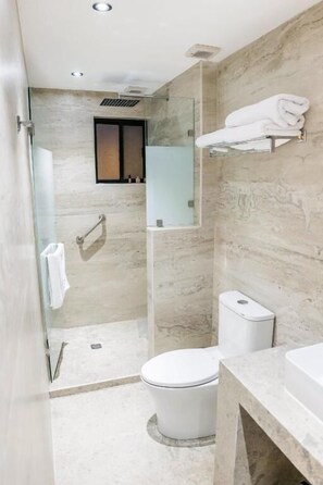 Une salle de bain moderne avec une douche à parois de verre, des toilettes et un meuble-lavabo doté d’un porte-serviettes.