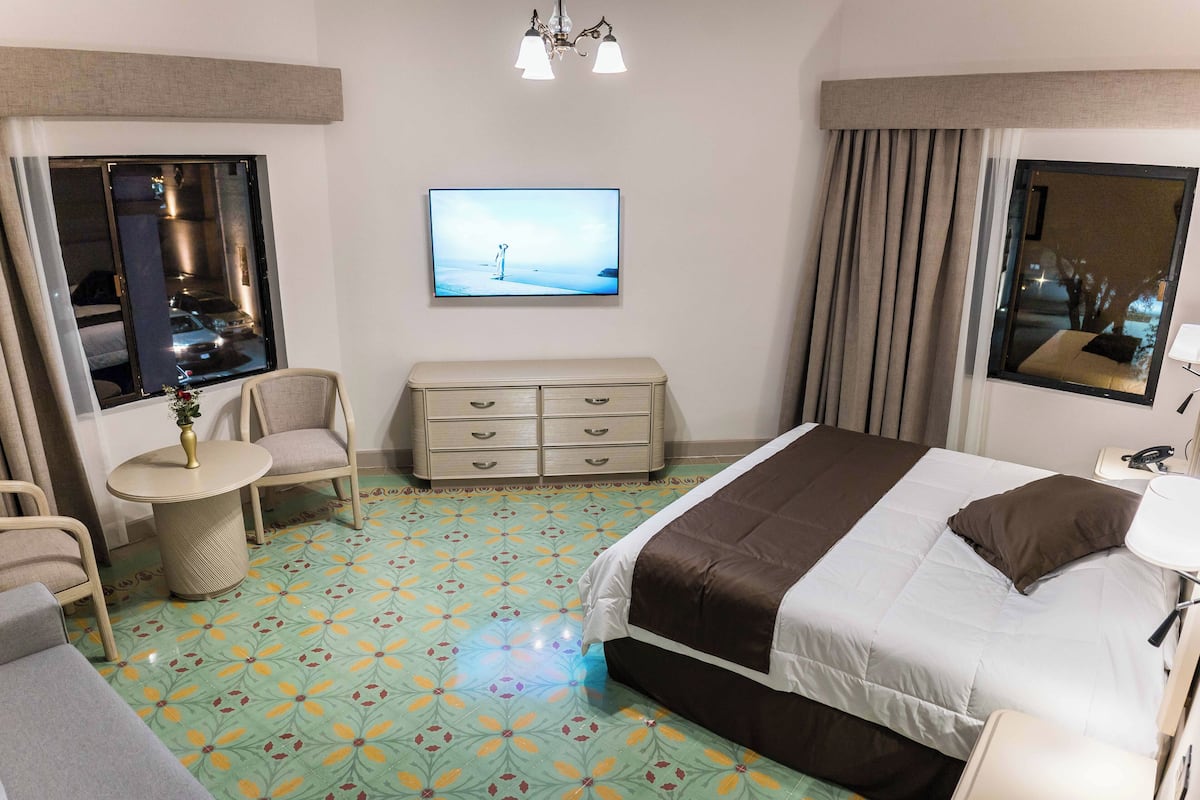 A hotel room with a bed, a TV, a desk, and a chair.