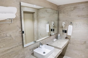 Un baño moderno con un espejo grande, dos lavamanos y ganchos para toallas.