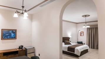A hotel room with a desk, chair, bed, and artwork.