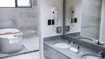 A modern bathroom with a bathtub, two sinks, and a large mirror.