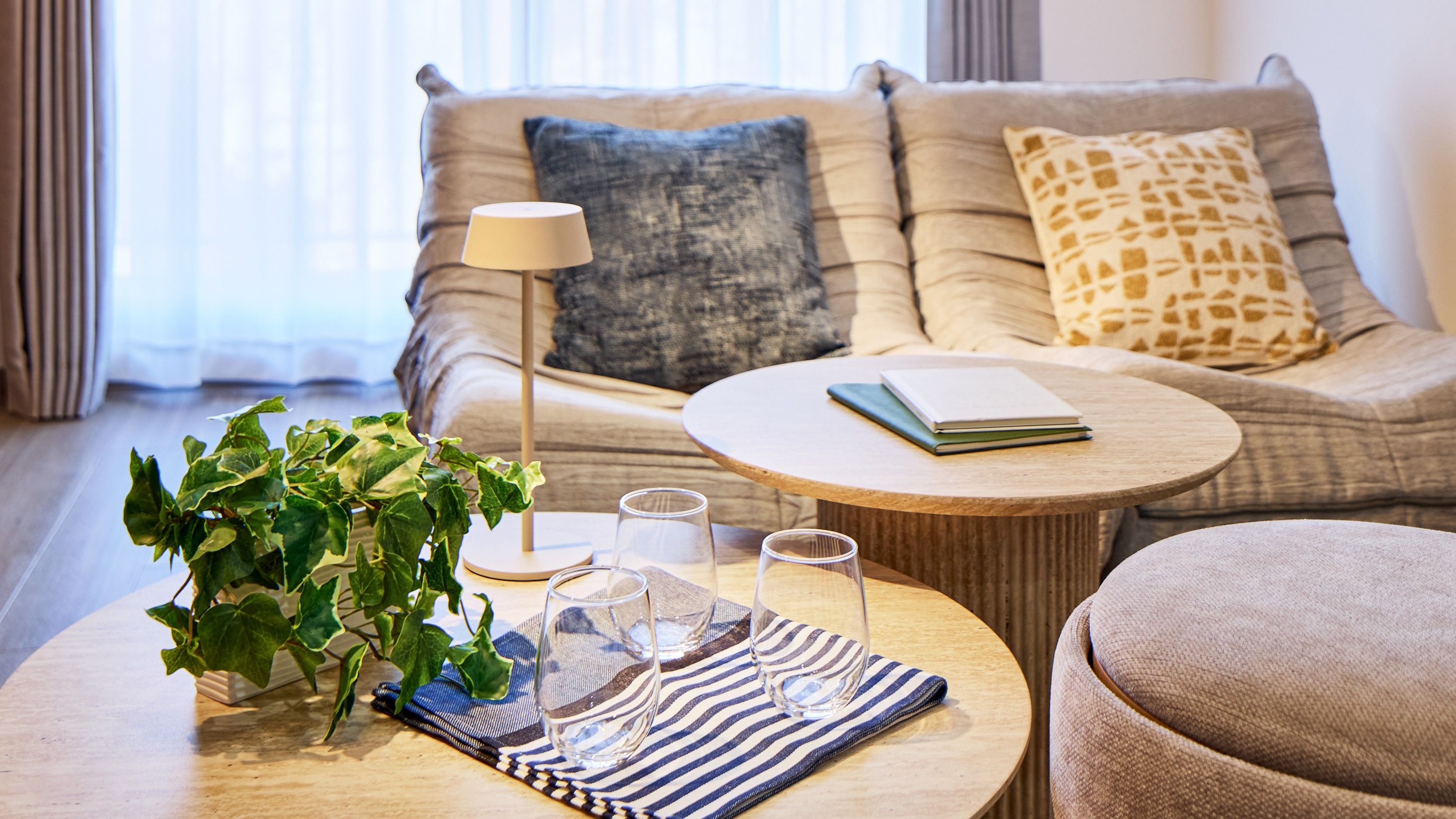 A living room with a sofa, a round coffee table, a lamp, a plant, and a book.