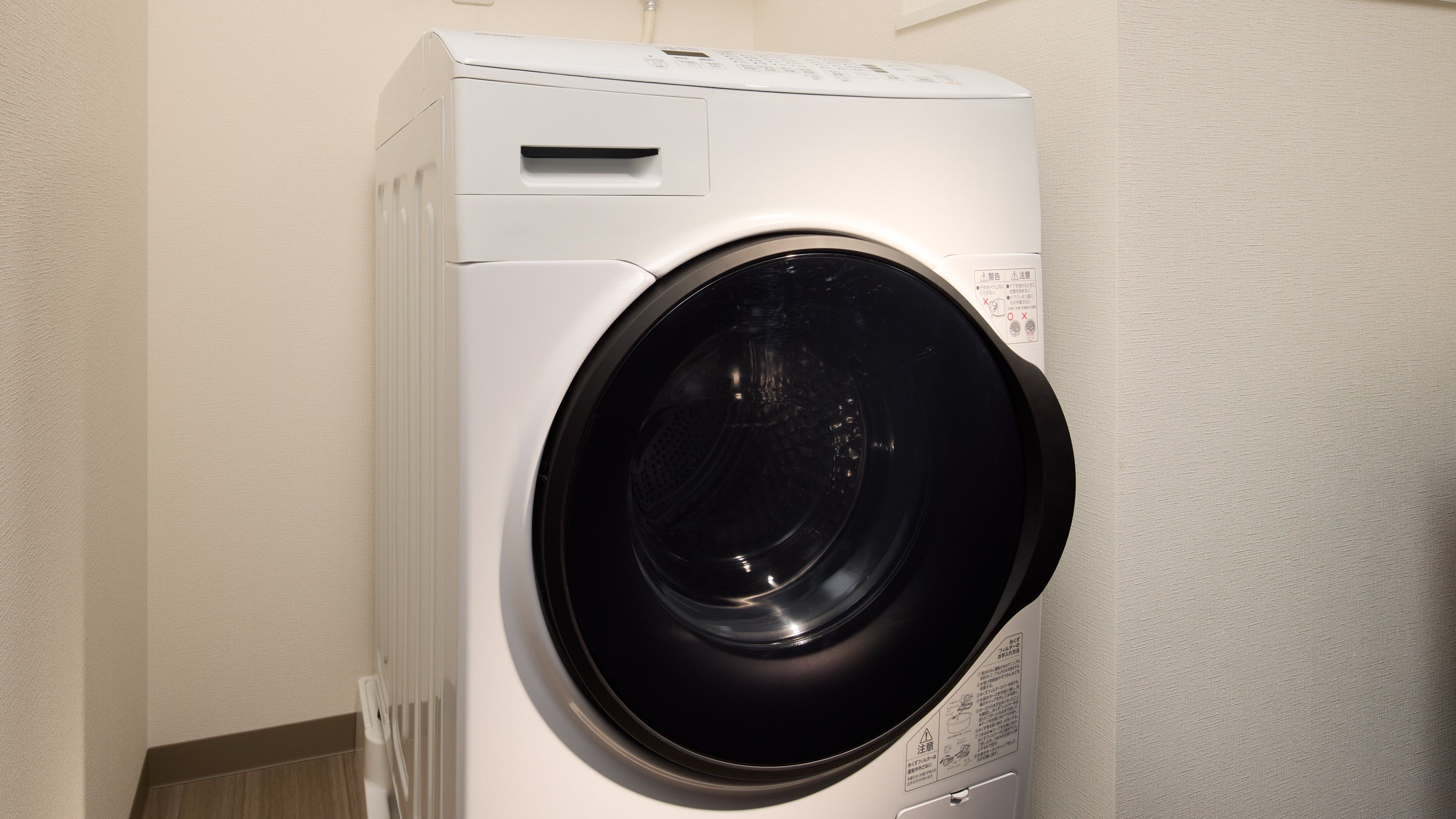 A front view of a white, wall-mounted, front-loading washing machine.