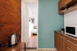 A compact kitchen with a kettle, a microwave, and wooden cabinets. - Private Room | Heart of Polanco (Mexico City)