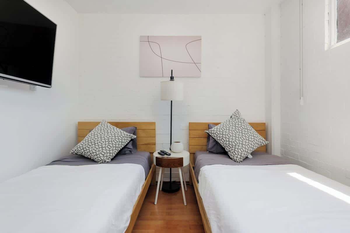 A hotel room with two beds, a TV, a lamp, and a small table.