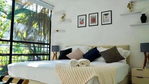 A bedroom with a bed, bedside tables, a window with a view of trees, and wall art. - 4BR apartment | Private Balcony · Near Masaryk (Mexico City)