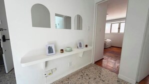 A hallway with a white wall, a shelf with a picture frame, a small bowl, and a white object. - 4BR apartment | Private Balcony · Near Masaryk (Mexico City)