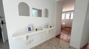 A hallway with a white wall, a shelf with a picture frame, a small bowl, and a white object. - 4BR apartment | Private Balcony · Near Masaryk (Mexico City)