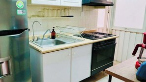 A compact kitchen with a stainless steel refrigerator, a sink with a soap dispenser, a wire rack, a stove, and a microwave. - Boutique Apt | Polanco - Masaryk (Mexico City)
