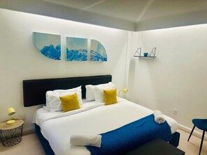 A hotel room with a bed, a bedside table with a lamp, a chair, and a wall-mounted shelf. - PH in Polanco | Near Masaryk · 4BR · Balcony (Mexico City)