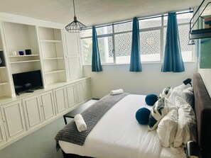 A hotel room with a bed, a television, and a window with curtains. - PH in Polanco | Near Masaryk · 4BR · Balcony (Mexico City)