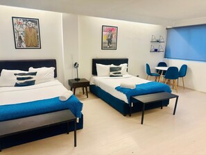 Ein Hotelzimmer mit zwei Betten, einem Schreibtisch, Stühlen und Bildern an den Wänden.