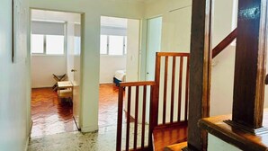 Un interior espacioso con escalera de madera, un comedor y vistas a un dormitorio a través de una puerta abierta.