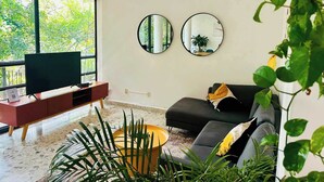 Una sala de estar moderna con un ventanal grande, un televisor de pantalla plana, un sofá y dos espejos montados en la pared.