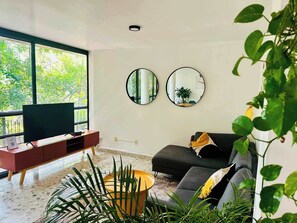 A modern living room with a large window, a flat-screen TV, a sofa, and two wall-mounted mirrors. - Two-Level PH | Polanco · Near Masaryk · 4BR (Mexico City)