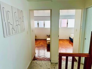 A hallway with a herringbone floor leading to a room with a bed and a window. - Two-Level PH | Polanco · Near Masaryk · 4BR (Mexico City)