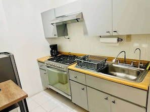 A compact kitchen with a gas stove, oven, and a sink. - Two-Level PH | Polanco · Near Masaryk · 4BR (Mexico City)