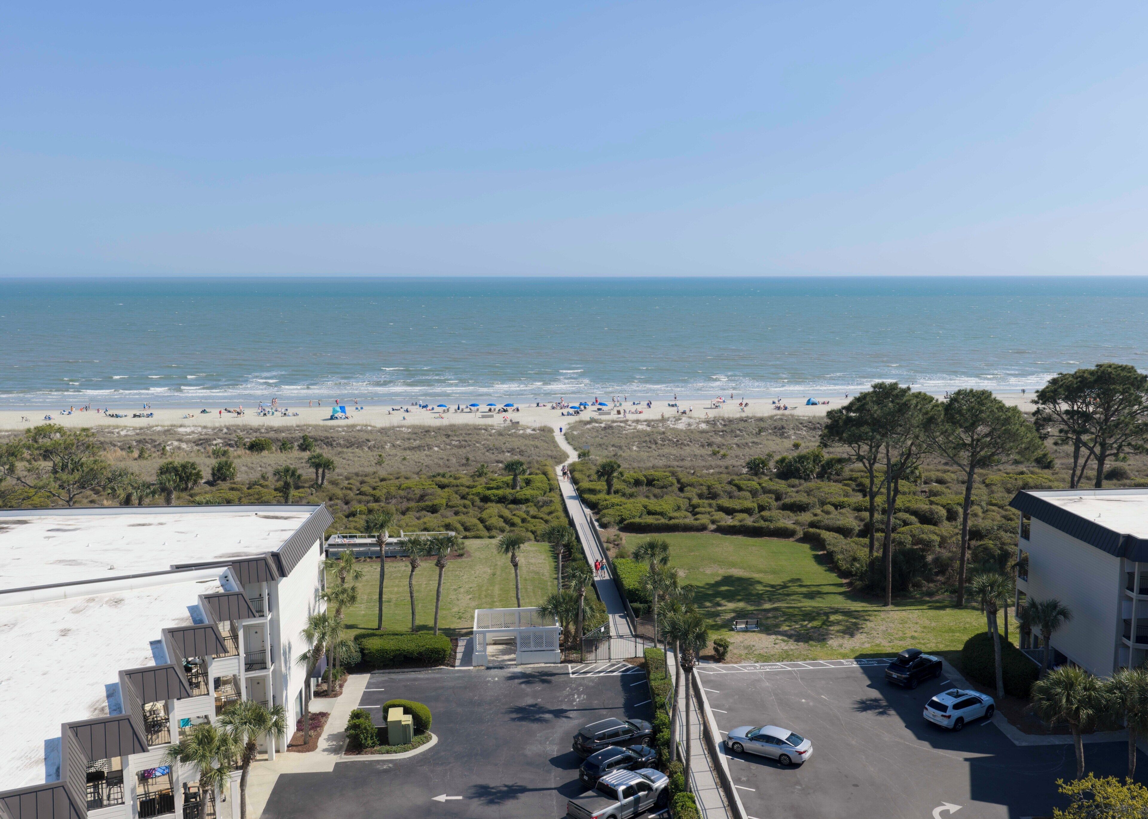 Vue sur la plage depuis un immeuble doté d’un parking et d’un chemin menant à la plage.