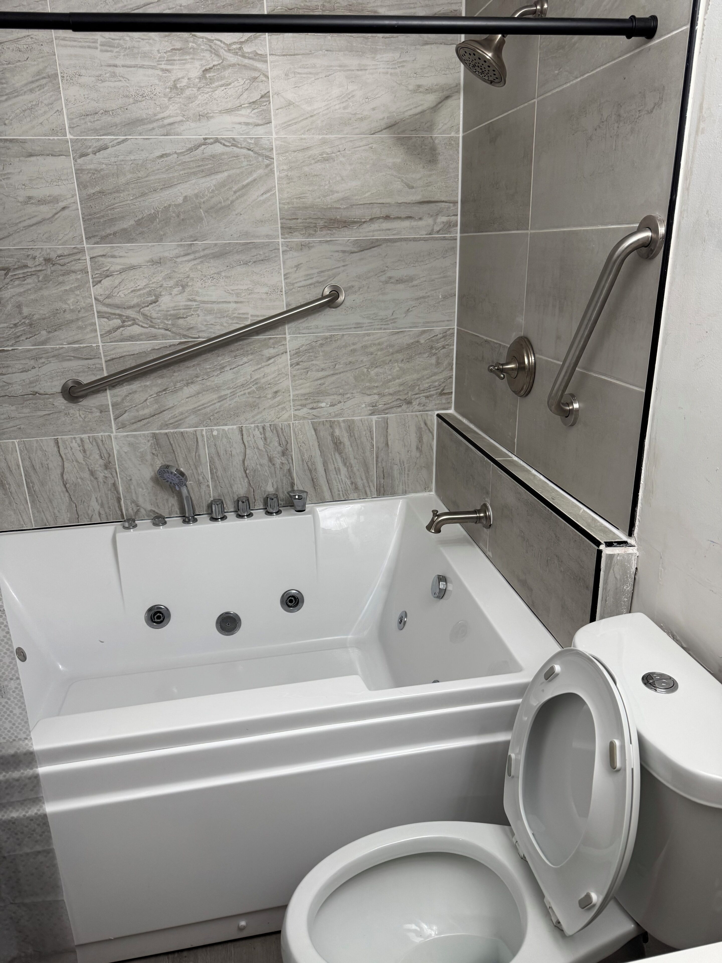 Een moderne badkamer met een bad, toilet en douche.