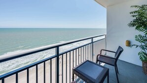 Ein Balkon mit Blick auf den Ozean, ein Korbstuhl-Tisch, zwei Stühle und ein Blumentopf.