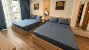 A hotel room with two beds, a bedside table with a lamp, and a mirror. - Elene Hotel (Phu Quoc)