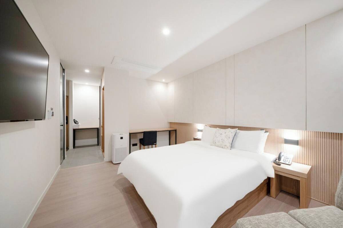 Quarto de hotel moderno com uma cama grande, uma escrivaninha, uma cadeira e uma televisão de tela plana.