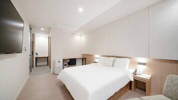 Quarto de hotel moderno com uma cama grande, uma escrivaninha, uma cadeira e uma televisão de tela plana.