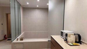 Un bagno moderno con box doccia in vetro, un mobile lavabo con forno a microonde, tazze da caffè e bollitore.