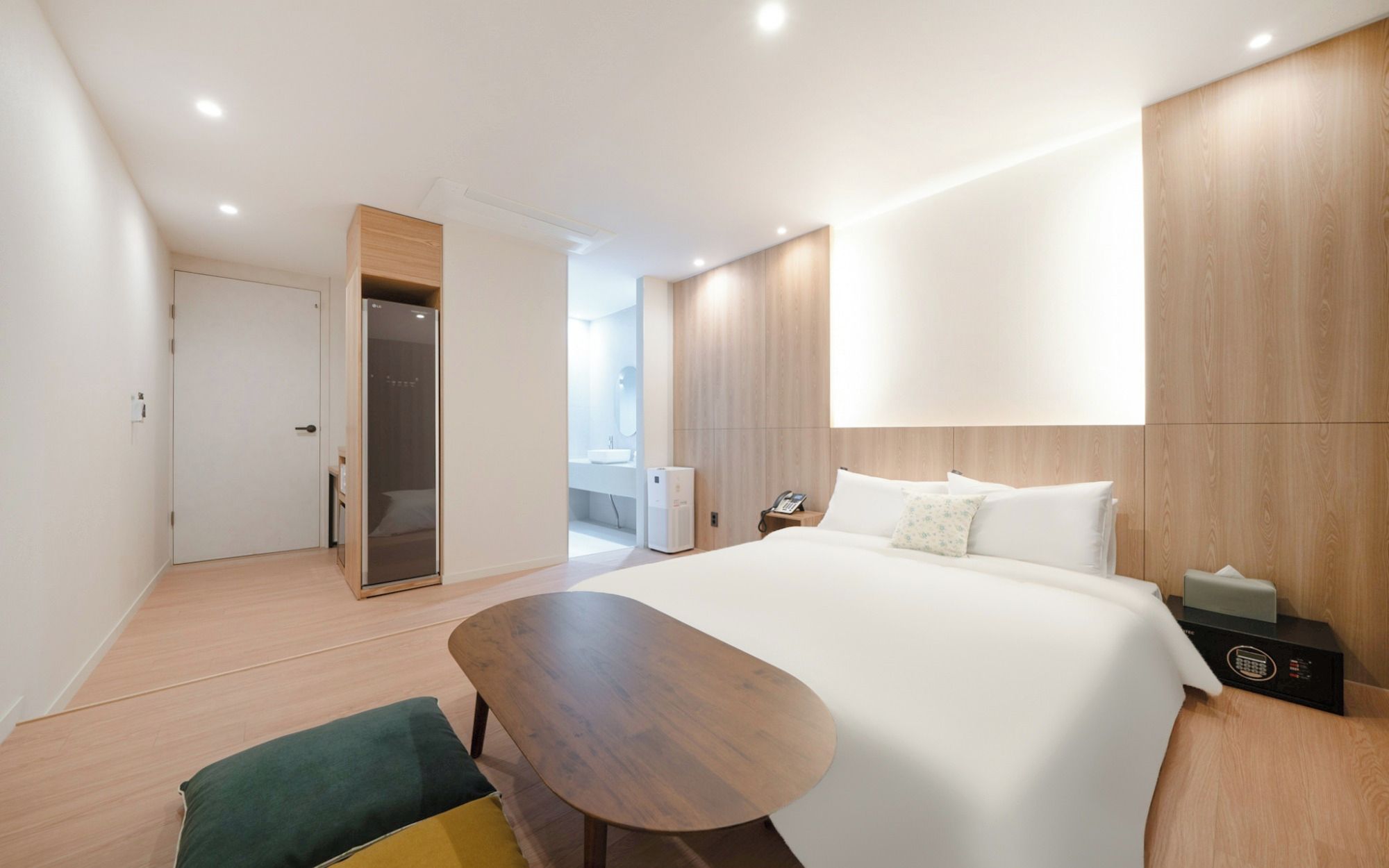 Quarto de hotel moderno com uma cama grande, escrivaninha de madeira, um espaço de estar pequeno e um closet espaçoso.