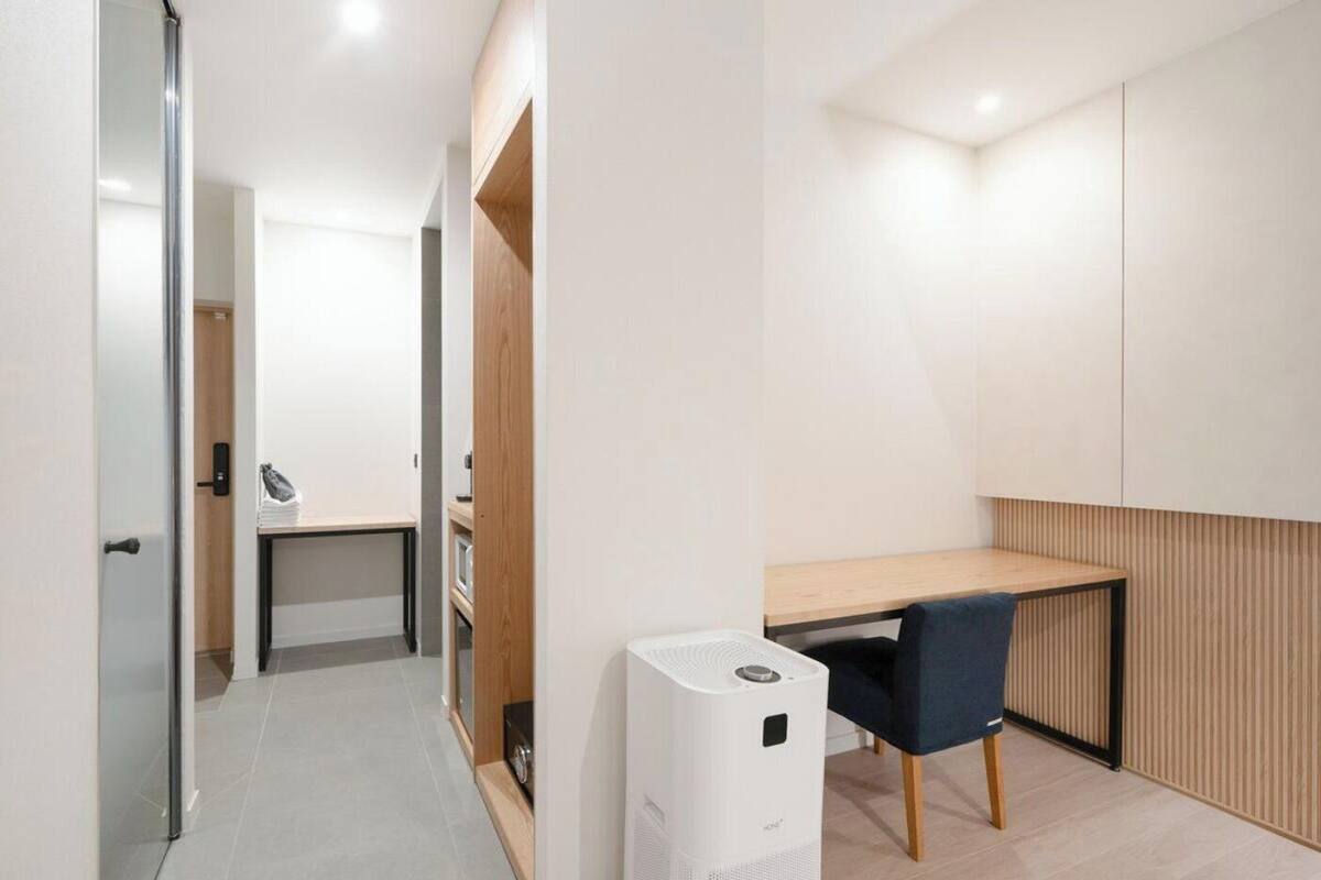 Quarto moderno com escrivaninha, cadeira e um pequeno aquecedor.