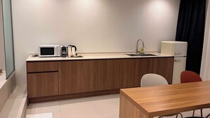 Una cucina compatta con forno a microonde, macchina del caffè e lavello.