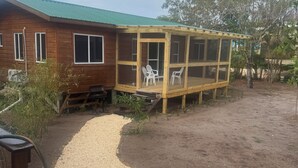 Ein Holzhaus mit überdachter Terrasse, einem Schotterweg und einem Garten mit roten Blumen.