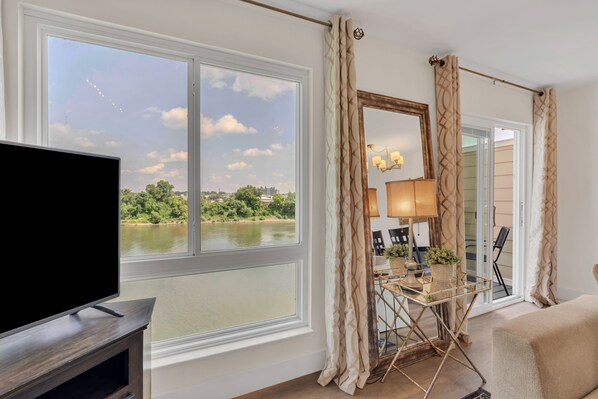 Ein Zimmer mit Fernseher, einem Tisch mit Lampe und Seeblick.