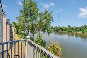 Ein Balkon mit Blick auf einen Fluss, Bäume und ein Gebäude mit einem Balkon.
