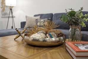 A living room with a round metal bowl on a wooden table, a book, and a vase with green plants. - Spacious 5BR in vibrant area, walk to cafes, restaurants & galleries (Detroit)