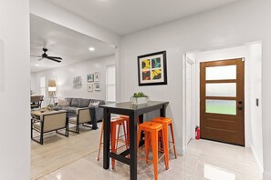 A modern living room with a dining area, a ceiling fan, and a door with frosted glass panels.
