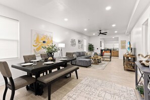 A spacious living area with a dining table, sofas, and a kitchen in the background. - Spacious 5BR in vibrant area, walk to cafes, restaurants & galleries (Detroit)
