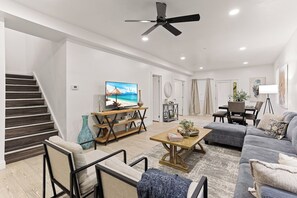 Un salon moderne avec un escalier, un téléviseur à écran plat, une table basse et un canapé.